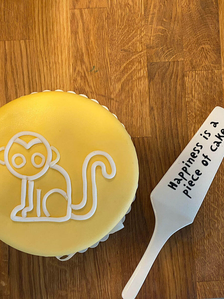 Gelbe Torte mit einem Monkey-Icon auf einer Holzküchentheke und Tortenheber
