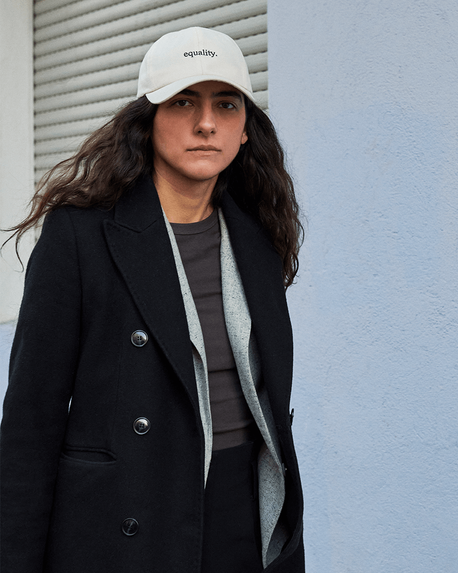 Frau mit Mantel tragt eine equality cap