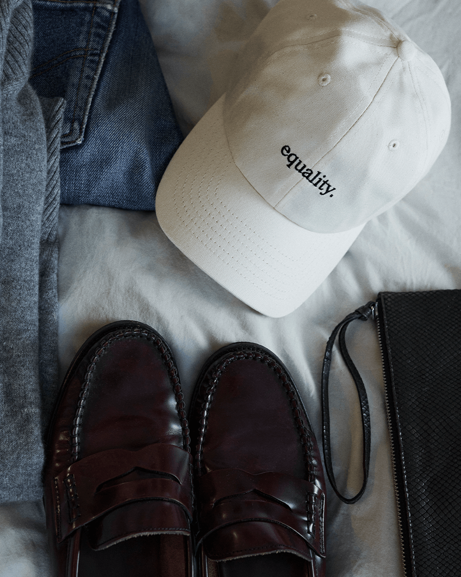 Kleidungsstücke auf einem Bett – auch Schuhe, Hose und eine equality cap